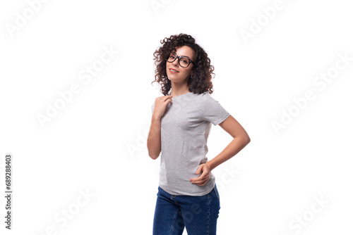 young charming slim 30 year old caucasian woman with curly black hair in a gray t-shirt on a white background with copy space © Ivan Traimak