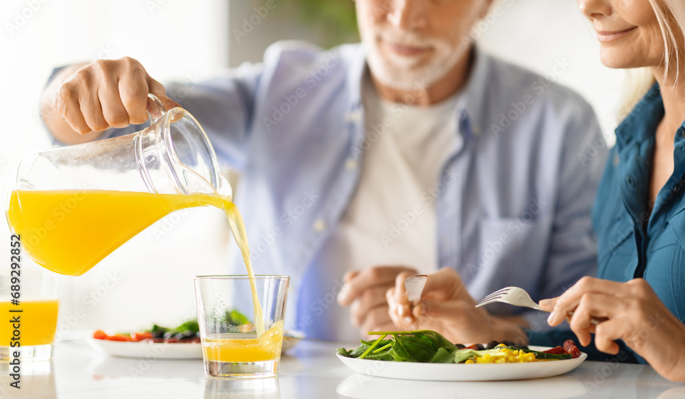 Elderly spouses having breakfast together in kitchen, cropped shot Elderly spouses having breakfast together in kitchen, cropped shot