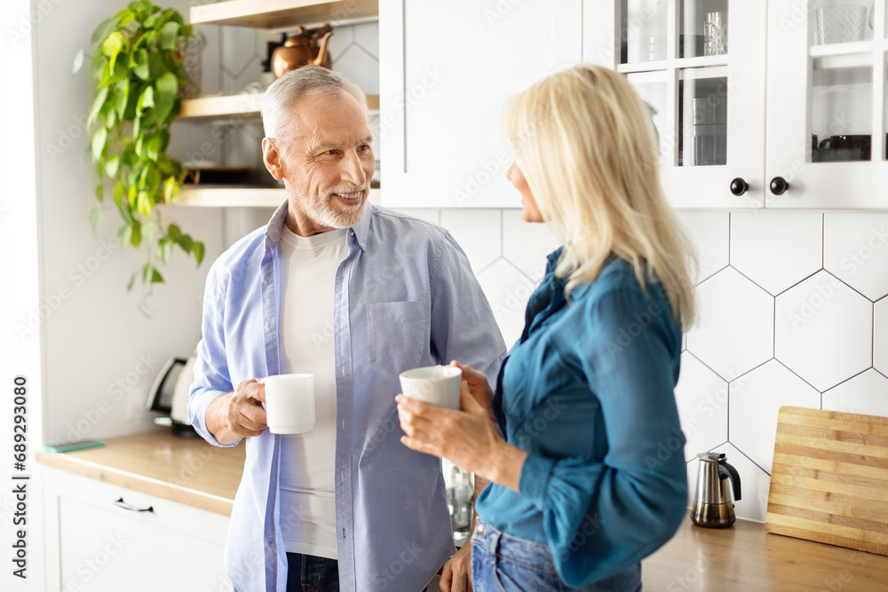 Fototapeta premium Happy elderly couple drinking morning coffee in kitchen