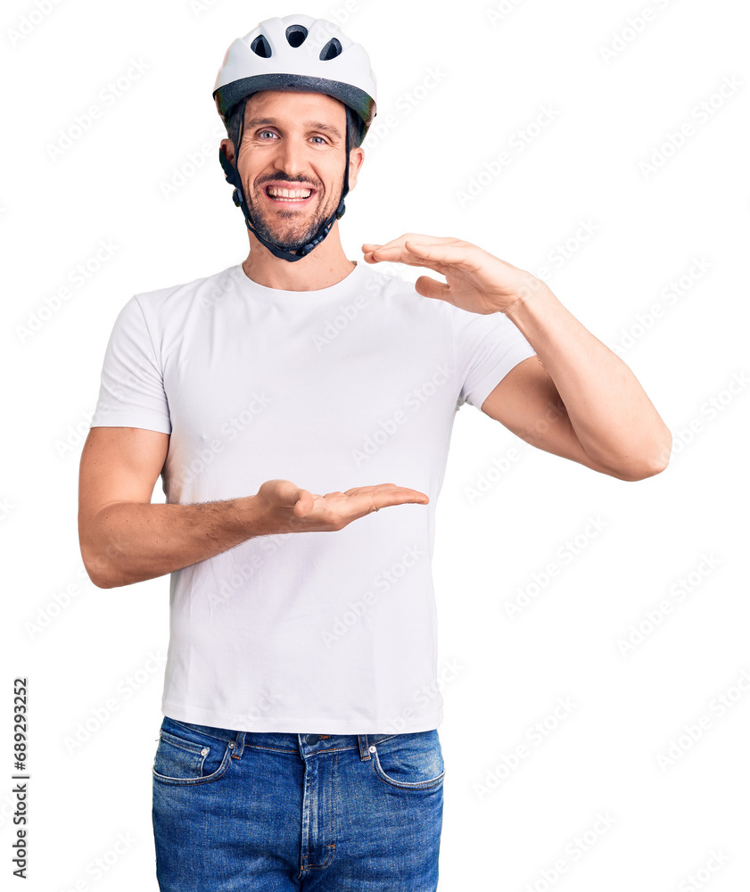 Young handsome man wearing bike helmet gesturing with hands showing big and large size sign, measure symbol. smiling looking at the camera. measuring concept. Young handsome man wearing bike helmet gesturing with hands showing big and large size sign, measure symbol. smiling looking at the camera. measuring concept.
