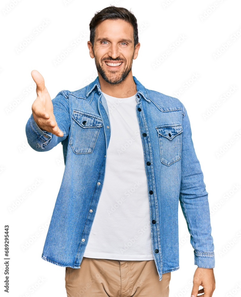 Young handsome man wearing casual denim jacket smiling friendly offering handshake as greeting and welcoming. successful business. Young handsome man wearing casual denim jacket smiling friendly offering handshake as greeting and welcoming. successful business.