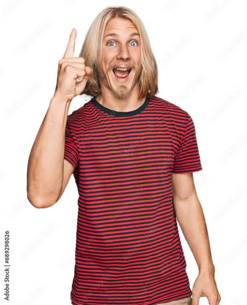 Caucasian man with blond long hair wearing casual striped t shirt pointing finger up with successful idea. exited and happy. number one. Caucasian man with blond long hair wearing casual striped t shirt pointing finger up with successful idea. exited and happy. number one.