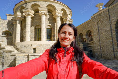 A happy tourist takes a selfie with a smartphone camera in front of the Semashko mud baths, Russia. Mudbath named after Semashko. Built in 1913-1915. Essentuki, Stavropol Territory, Russia