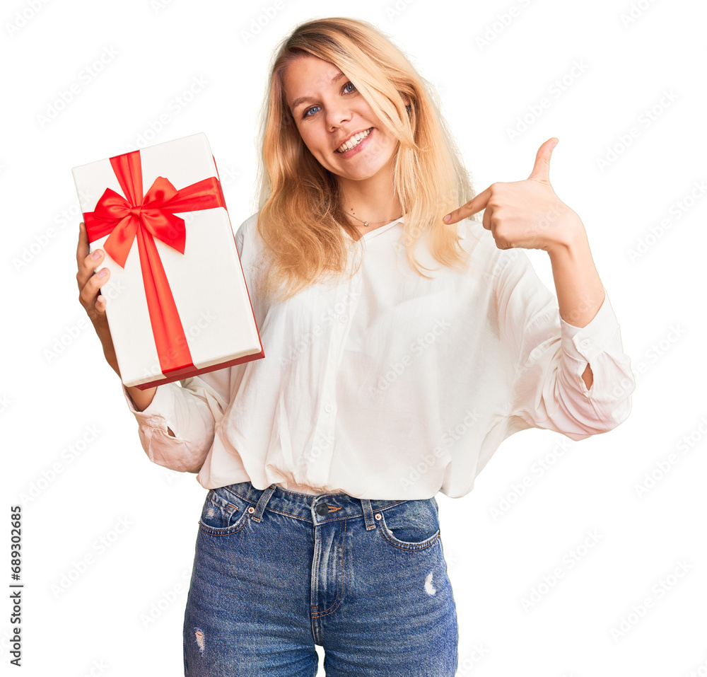 Young beautiful blonde woman holding gift serious face thinking about question with hand on chin, thoughtful about confusing idea Young beautiful blonde woman holding gift serious face thinking about question with hand on chin, thoughtful about confusing idea