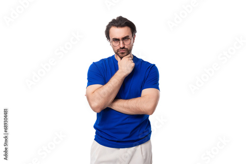 young suspicious brunette european man with a well-groomed beard in a blue t-shirt on a white background with copy space