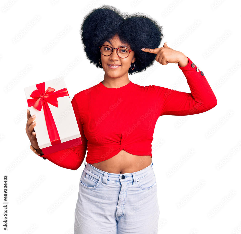 Young african american girl holding gift smiling pointing to head with one finger, great idea or thought, good memory Young african american girl holding gift smiling pointing to head with one finger, great idea or thought, good memory