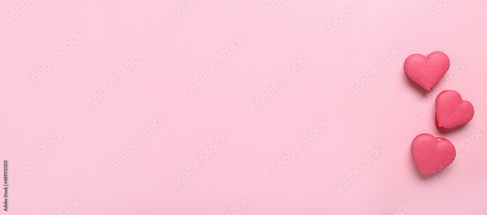 Sweet heart-shaped macarons on pink background with space for text