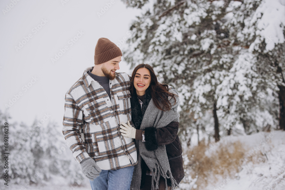 A young happy and loving couple walking in a winter snowy forest in the mountains A young happy and loving couple walking in a winter snowy forest in the mountains
