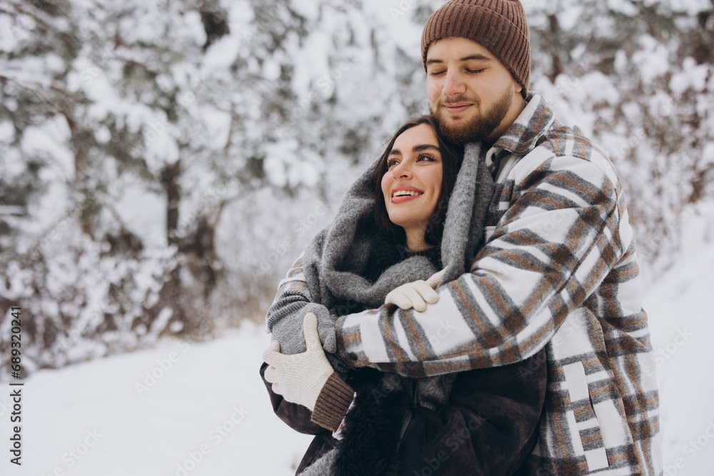 A young happy and loving couple is having fun in a snowy forest in winter. A young happy and loving couple is having fun in a snowy forest in winter.