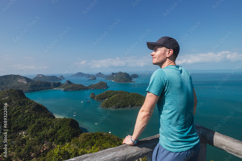 Happy man is enjoying amazing view from top of hill. Group of tropical islands in sea near Koh Samui in Thailand..