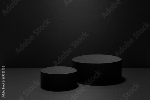 Abstract stage mockup with two black round podiums with light rays for presentation cosmetic products, goods, advertising, design on black background. Abstract scene in fashion modern event style.