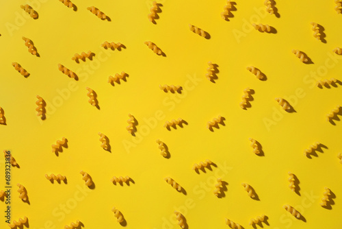 Composition with uncooked elbow pasta on yellow background