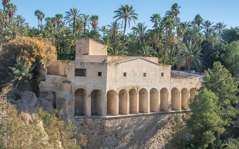 The view of buttresses supported by twelve Renaissance arches of the 18th century Moli del Real old flour mill with the Islamic origins, surrounded by the palm trees in Elche, Alicante, Spain