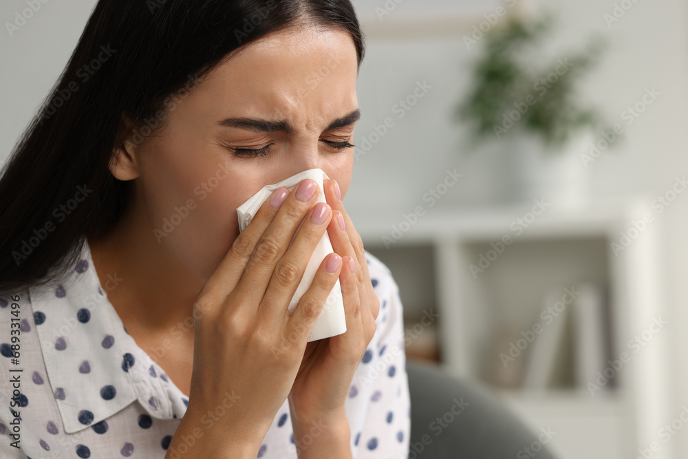 Suffering from allergy. Young woman blowing her nose in tissue indoors, closeup. Space for text Suffering from allergy. Young woman blowing her nose in tissue indoors, closeup. Space for text