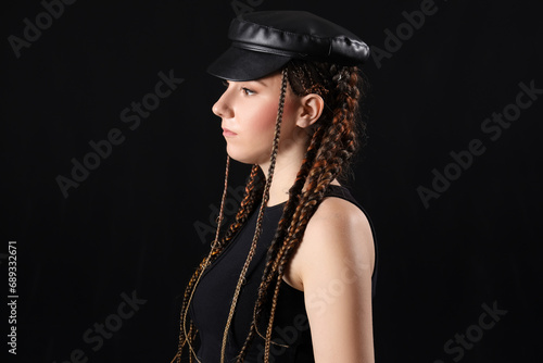 Young woman with dreadlocks in stylish hat on dark background, closeup