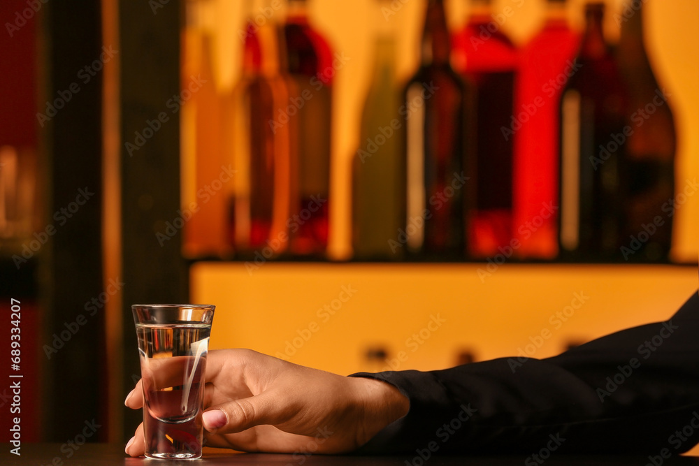 Female hand with shot of cold vodka on table in bar
