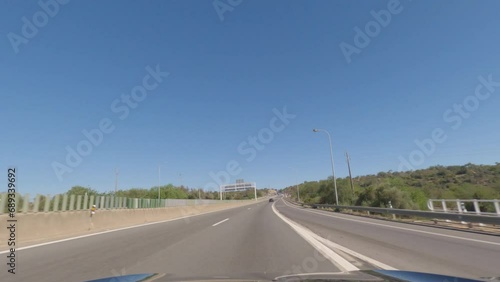 First person view, FPV, from dashcam of car driving along the Algarve Coast in Portugal towards Faro, driving on the highway. Road trip video in POV, with blue sky photo