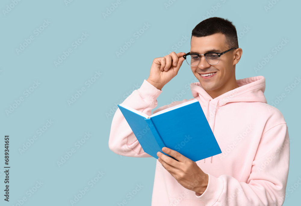 Handsome young man reading book on blue background Handsome young man reading book on blue background
