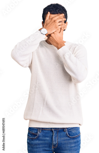 Young african amercian man wearing casual clothes covering eyes and mouth with hands, surprised and shocked. hiding emotion © Krakenimages.com
