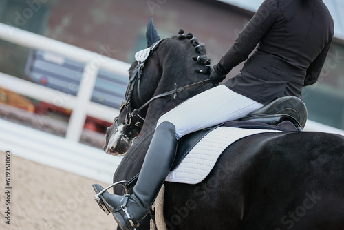 The rider's leg is a close-up of a dressage competition. Black Horse photo