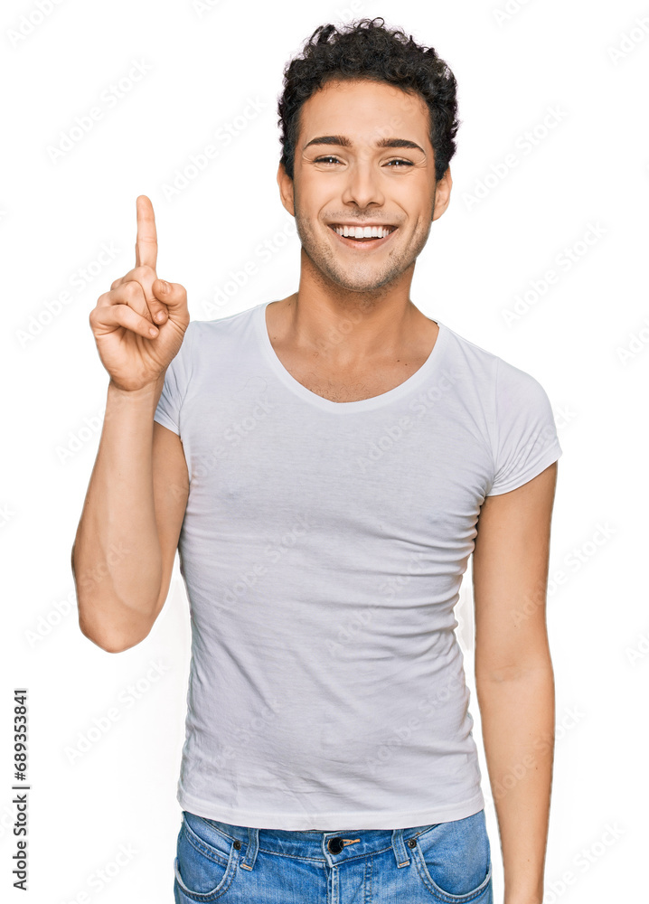 Young handsome man wearing casual white t shirt pointing finger up with successful idea. exited and happy. number one. Young handsome man wearing casual white t shirt pointing finger up with successful idea. exited and happy. number one.