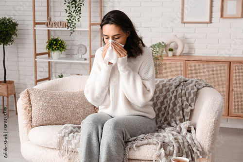 Sick young woman with tissue at home