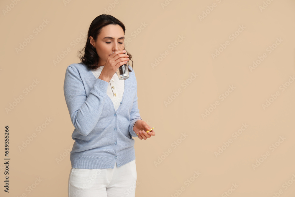 Sick young woman with pills and glass of water on beige background Sick young woman with pills and glass of water on beige background