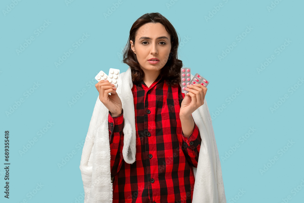 Sick young woman with pills on blue background Sick young woman with pills on blue background