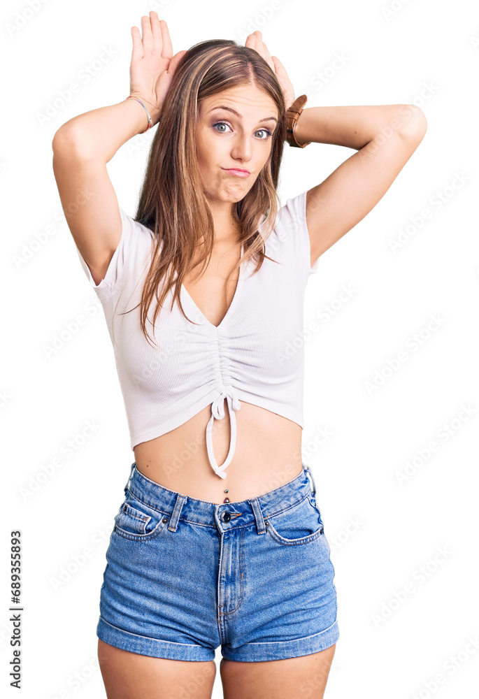 Young beautiful blonde woman wearing casual white tshirt doing bunny ears gesture with hands palms looking cynical and skeptical. easter rabbit concept. Young beautiful blonde woman wearing casual white tshirt doing bunny ears gesture with hands palms looking cynical and skeptical. easter rabbit concept.