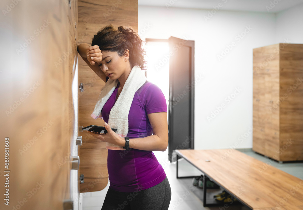 Serious attractive tired sportswoman checking notifications on smart phone after sports training. Serious attractive tired sportswoman checking notifications on smart phone after sports training.