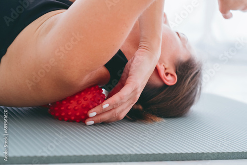 Woman lying on small balls to eliminate back pain, massage stiff muscles and thoracic back pain, perform exercises to relieve pain in spine. Relaxation and stretching of muscles photo