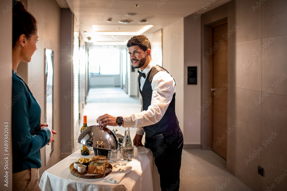 Male room service hotel staff waiter serving tray to hotel guest Stock