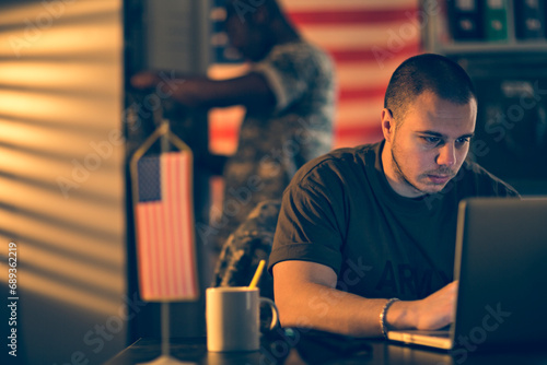 Army soldier working on laptop at military base photo
