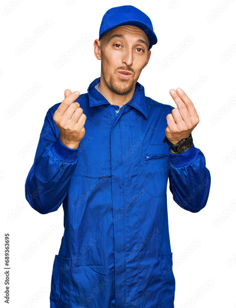 Bald man with beard wearing builder jumpsuit uniform doing money gesture with hands, asking for salary payment, millionaire business