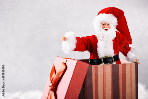 Santa Claus Toy in Christmas red gift box on snow over silver background © photopixel