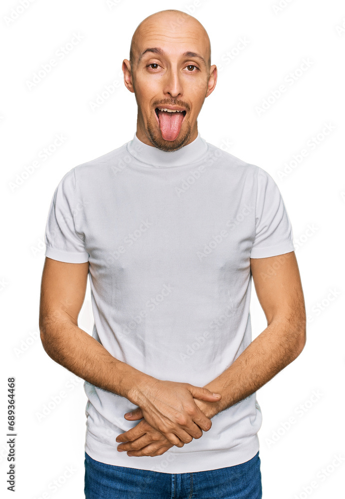 Bald man with beard wearing casual white t shirt sticking tongue out happy with funny expression. emotion concept. Bald man with beard wearing casual white t shirt sticking tongue out happy with funny expression. emotion concept.