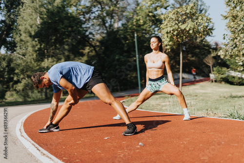 A Caucasian couple exercising in a park. They stretch and warm up before a vigorous workout. With persistence, they practice recreational sports and embrace a healthy lifestyle.