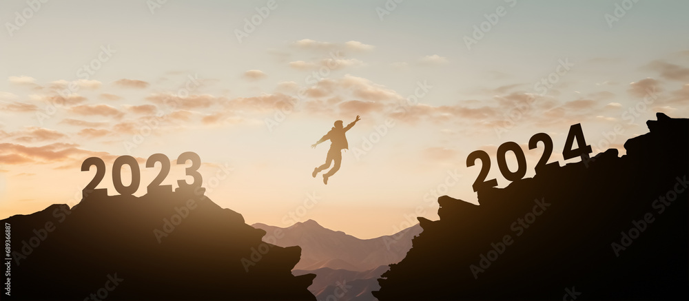 silhouette of a man jumping from one mountain to another leaving behind the year 2023 about to fall and reaching the new year 2024 - concept of setting goals for the next year