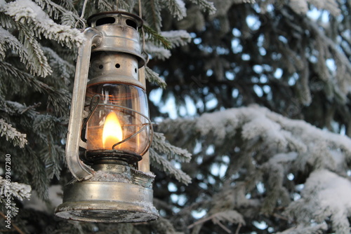 a winter kerosene lantern shines in the branches of a Christmas tree. © Yar