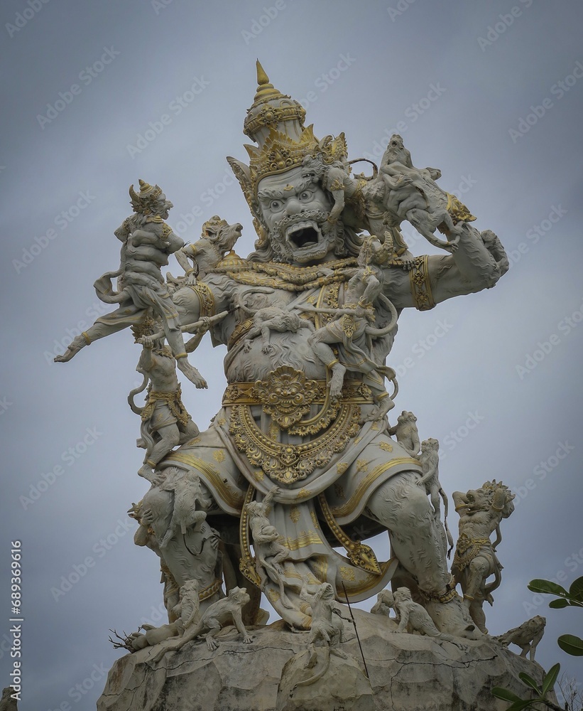 Majestic Asian bronze statue sits atop a large outcrop of rocks in an idyllic setting