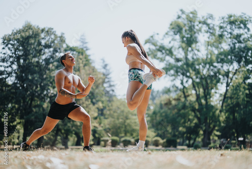 Fototapeta Naklejka Na Ścianę i Meble -  Caucasian couple engages in persistent outdoor exercise in the park. They motivate each other while training their muscles. Embodying positivity and sportsmanship.