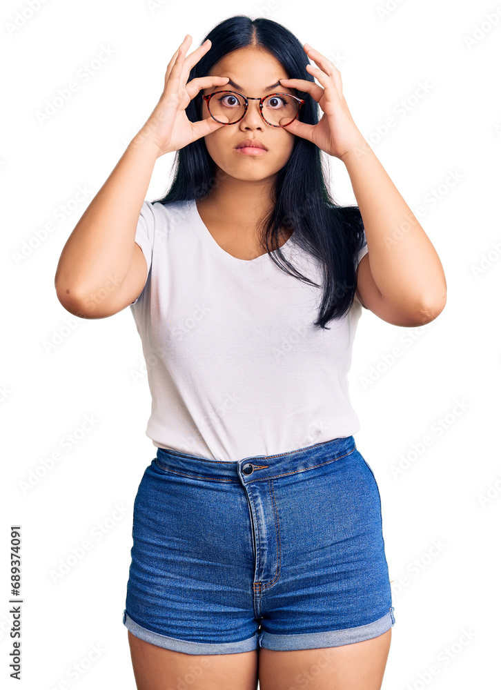 Young beautiful asian girl wearing casual clothes and glasses trying to open eyes with fingers, sleepy and tired for morning fatigue Young beautiful asian girl wearing casual clothes and glasses trying to open eyes with fingers, sleepy and tired for morning fatigue