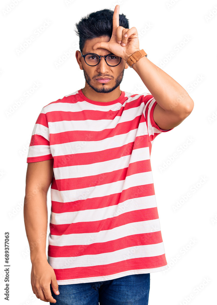 Handsome latin american young man wearing casual clothes and glasses making fun of people with fingers on forehead doing loser gesture mocking and insulting. Handsome latin american young man wearing casual clothes and glasses making fun of people with fingers on forehead doing loser gesture mocking and insulting.