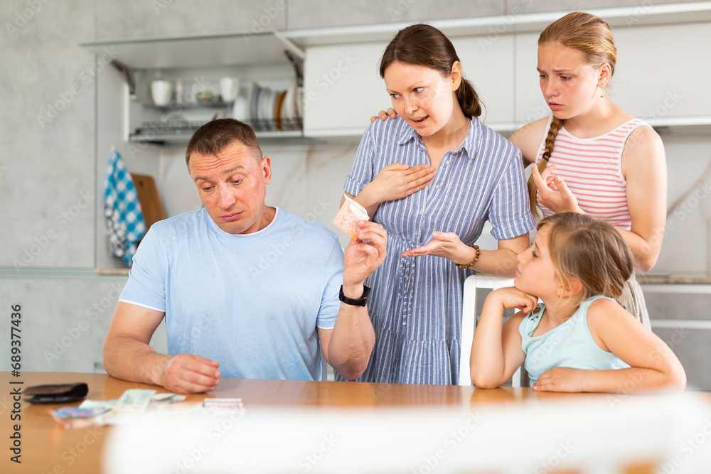 Dissatisfied husband and father give out pocket money to wife and children in home kitchen