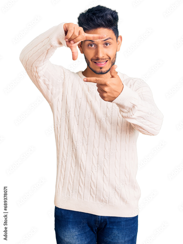 Handsome latin american young man wearing casual winter sweater smiling making frame with hands and fingers with happy face. creativity and photography concept. Handsome latin american young man wearing casual winter sweater smiling making frame with hands and fingers with happy face. creativity and photography concept.