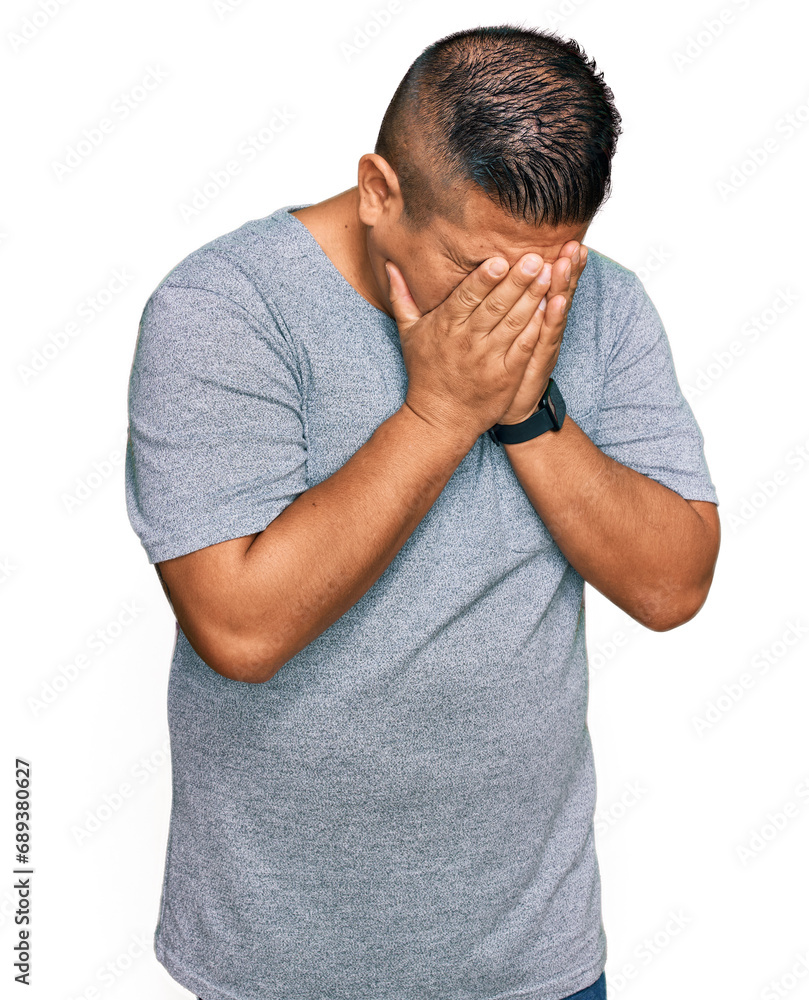 Young latin man wearing casual clothes with sad expression covering face with hands while crying. depression concept. Young latin man wearing casual clothes with sad expression covering face with hands while crying. depression concept.