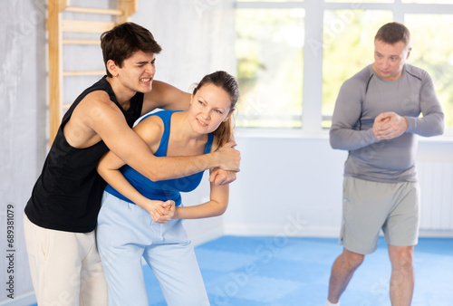 Guy and woman paired up and practice technique of strangulation to neutralize opponent and attacker. Class self-defense training in presence of experienced instructor