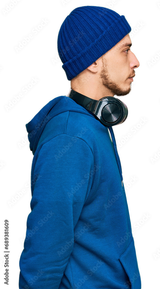 Hispanic young man wearing sweatshirt and wool hat looking to side, relax profile pose with natural face with confident smile. Hispanic young man wearing sweatshirt and wool hat looking to side, relax profile pose with natural face with confident smile.
