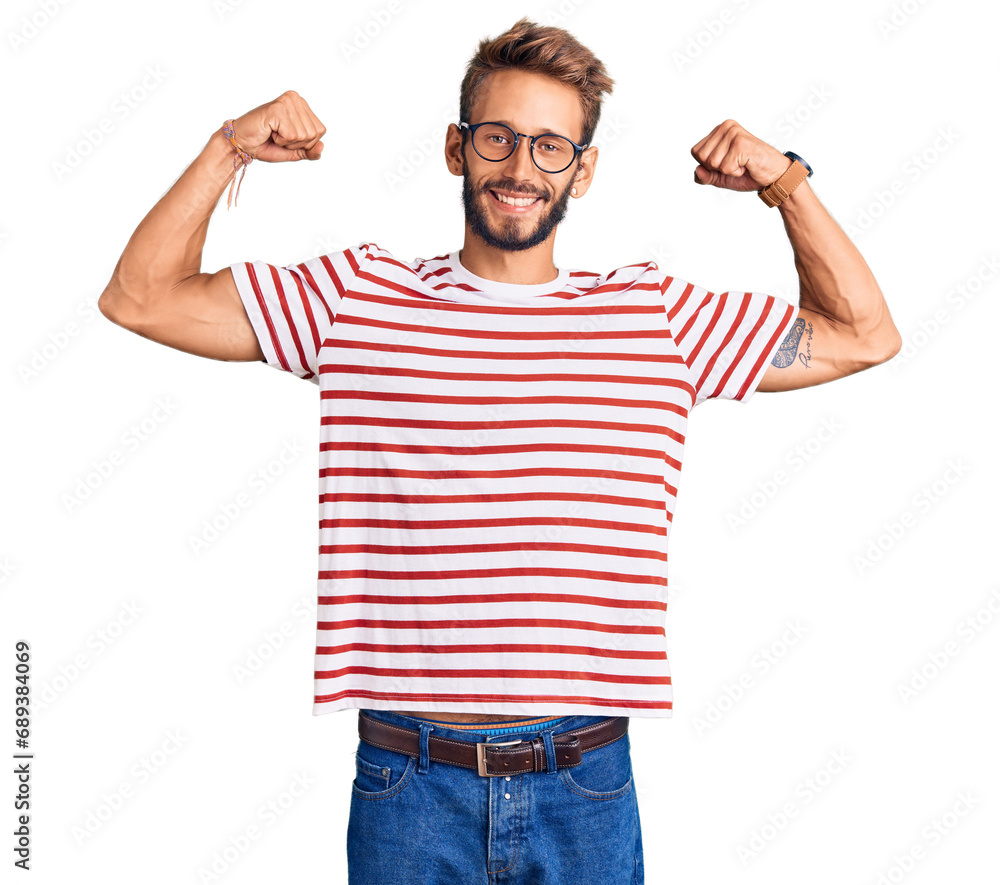 Fototapeta premium Handsome blond man with beard wearing casual clothes and glasses showing arms muscles smiling proud. fitness concept.