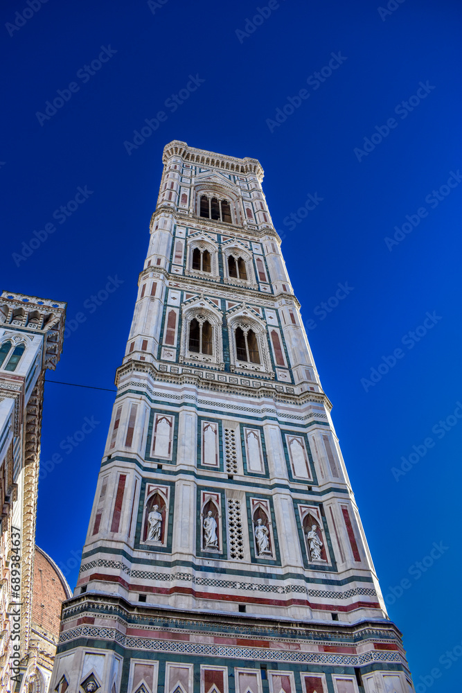 Florence, Italy - November 25, 2023 : the Giotto Bell Tower built near the Cathedral of Santa Maria del Fiore in Piazza del Duomo on blue sky